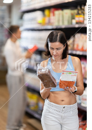 Adult woman chooses healthy food in store Adult woman chooses healthy food in store 134215283