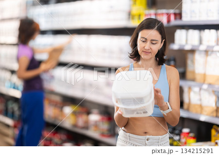 Adult woman buying jar of sports nutrition Adult woman buying jar of sports nutrition 134215291