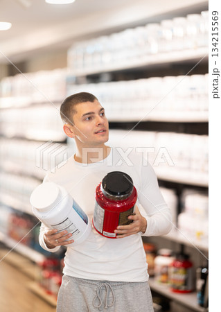 Young man buying jar of sports nutrition 134215569
