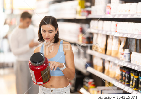 Woman chooses protein sports nutrition in store Woman chooses protein sports nutrition in store 134215871