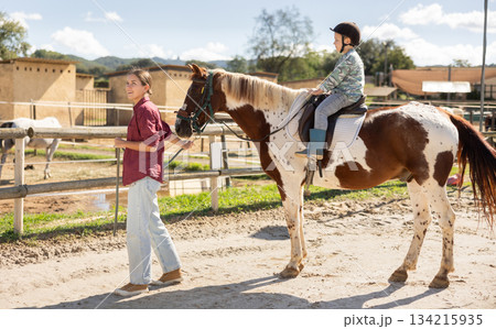 Young woman leading horse with boy riding 134215935