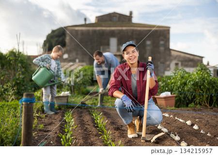 Woman with a garden tool near the beds in the garden 134215957