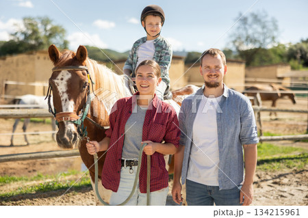Man and woman leading horse with boy on horseback 134215961