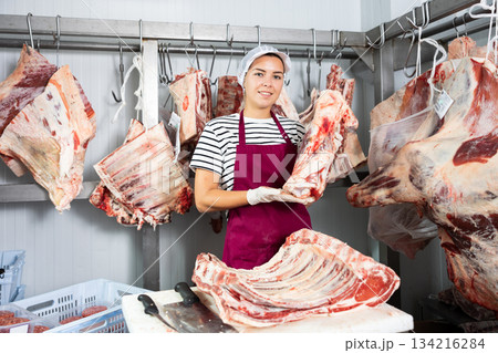 Female butcher is demonstraiting meat to clients indoors 134216284