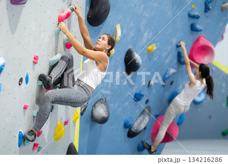 Sportive woman climbing on artificial rock wall in rock climbing gym Sportive woman climbing on artificial rock wall in rock climbing gym 134216286