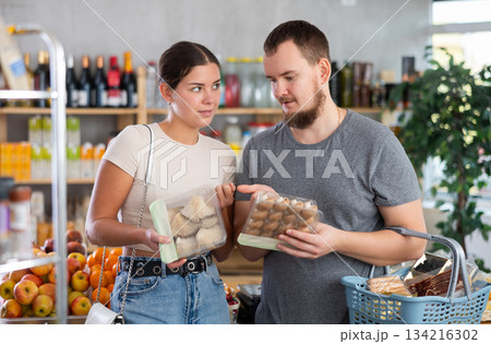 Couple man and woman choosing mushrooms in grocery store Couple man and woman choosing mushrooms in grocery store 134216302