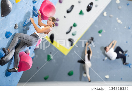 Young woman practicing rock climbing on climbing wall 134216323