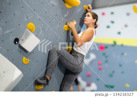 Young woman practicing rock climbing on climbing wall 134216327