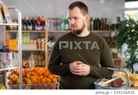 Grocery shopping at supermarket - man chooses somtething in grocery supermarket Grocery shopping at supermarket - man chooses somtething in grocery supermarket 134216418