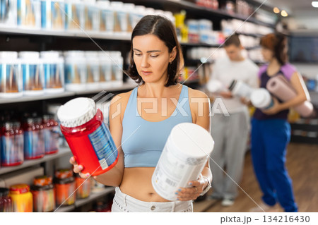 Adult woman buying jar of sports nutrition Adult woman buying jar of sports nutrition 134216430