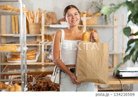 Young woman with baguette in bag in bakery Young woman with baguette in bag in bakery 134216509