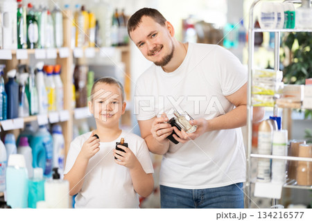 Dad and son client sniffs fragrance of perfume, chooses scent spray with pleasant smell 134216577