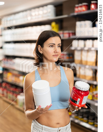 Woman chooses protein sports nutrition in store 134216635