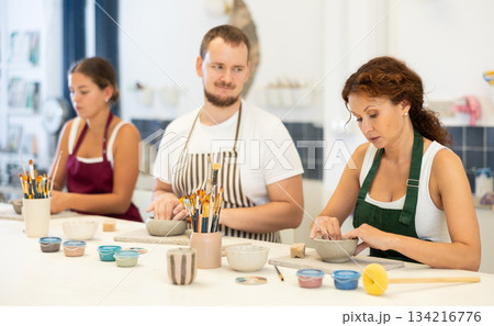Three pottery workshop workers sculpt from raw clay 134216776