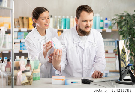Man pharmacist at computer communicate with girl colleague Man pharmacist at computer communicate with girl colleague 134216793