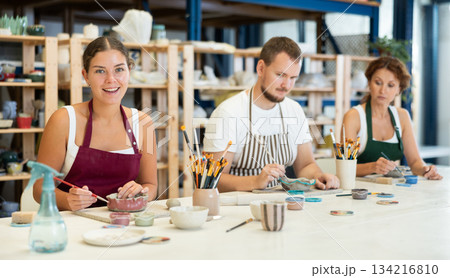 Three craftsperson are busy painting clay products Three craftsperson are busy painting clay products 134216810