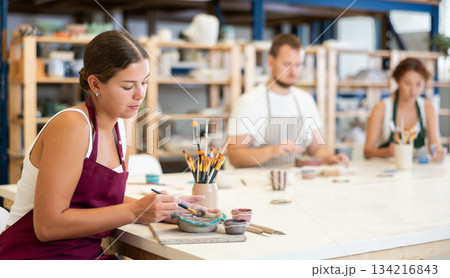 Three craftsperson are busy painting clay products Three craftsperson are busy painting clay products 134216843