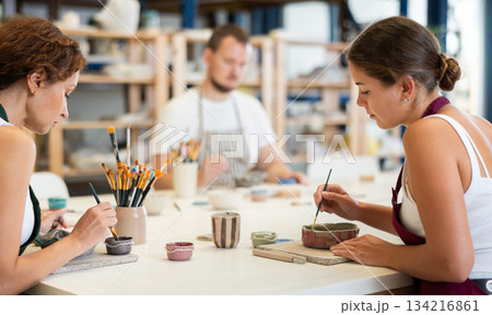 Three craftsperson are busy painting clay products 134216861