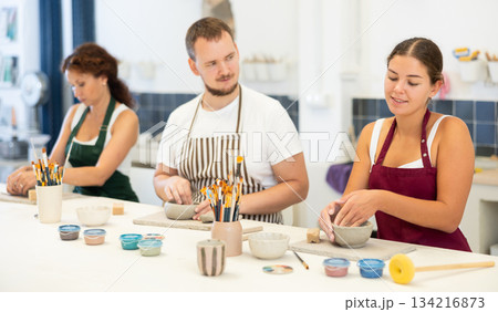 Three pottery workshop workers sculpt from raw clay Three pottery workshop workers sculpt from raw clay 134216873
