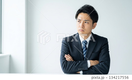腕を組み厳しい表情で判断するビジネスマン 134217556