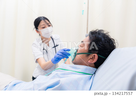 人工呼吸器をつけた患者のケアをする看護師の女性 134217557