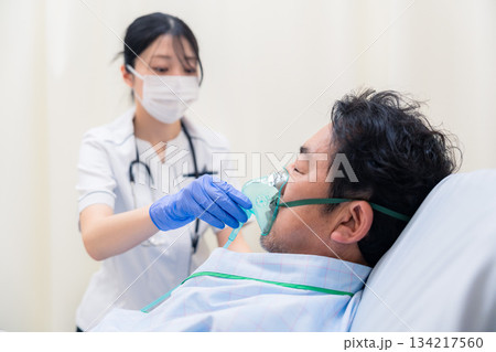 人工呼吸器をつけた患者のケアをする看護師の女性 人工呼吸器をつけた患者のケアをする看護師の女性 134217560