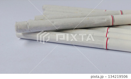 Several white cigarettes were neatly arranged on a clean white surface. 134219506
