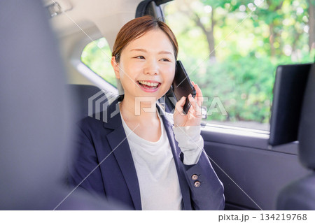 タクシーに乗って電話をする若い営業の女性 134219768