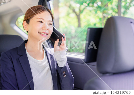 タクシーに乗って電話をする若い営業の女性 134219769