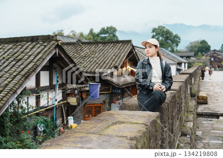 Happy woman traveler travel in Dujiangyan city. Tourist sightseeing the Ming City Wall at Guanxian Ancient City near Chengdu. Landmark and popular for tourism attraction in Sichuan, China Happy woman traveler travel in Dujiangyan city. Tourist sightseeing the Ming City Wall at Guanxian Ancient City near Chengdu. Landmark and popular for tourism attraction in Sichuan, China 134219808