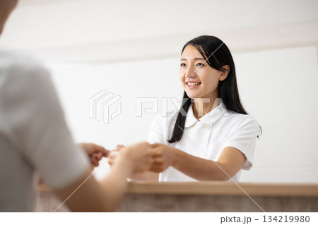 受付でカードを受け取る白衣姿の女性 受付でカードを受け取る白衣姿の女性 134219980