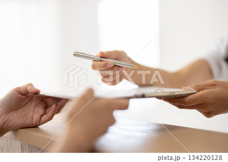 問診票とペンを手渡す手元のクローズアップ 問診票とペンを手渡す手元のクローズアップ 134220128