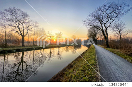 Enjoying the Serene Sunrise Reflections Along a Beautifully Calm Canal Path This Morning Enjoying the Serene Sunrise Reflections Along a Beautifully Calm Canal Path This Morning 134220444