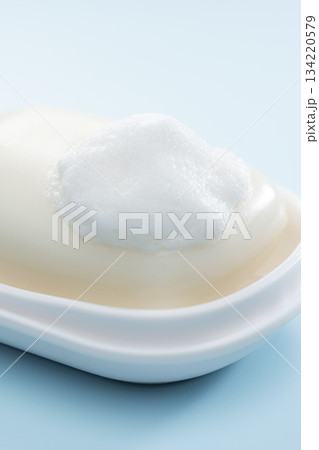 水色背景に映える泡の乗った固形石けんの清潔感あふれる日用品イメージ 水色背景に映える泡の乗った固形石けんの清潔感あふれる日用品イメージ 134220579