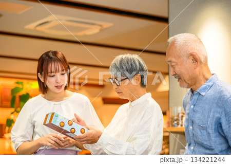 若い女性から老夫婦へお土産を渡す 若い女性から老夫婦へお土産を渡す 134221244