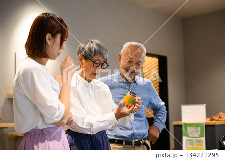 夫婦が店員から食品の説明を受ける 134221295