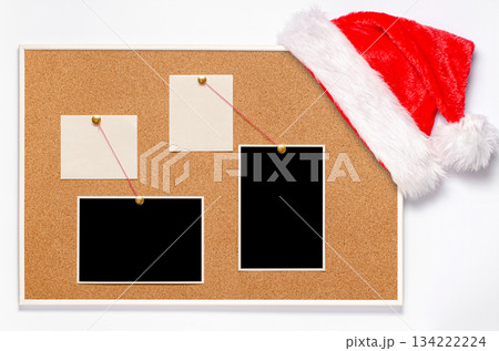 Blank paper notes and an empty photo are pinned to a cork board. Santa's hat on a cork board 134222224