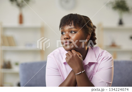 Close-up portrait of calm dreaming african american woman sitting on sofa at home Close-up portrait of calm dreaming african american woman sitting on sofa at home 134224074