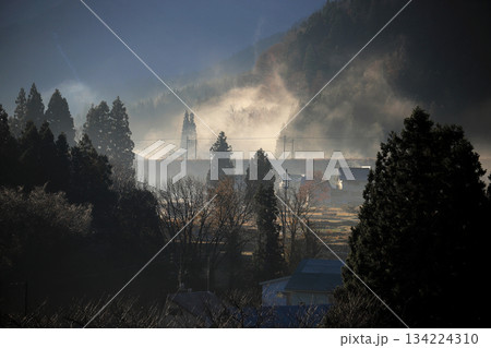 山間の集落 色付いた樹々 落葉樹 針葉樹の間に立ち込める霧と鉄道路線 134224310