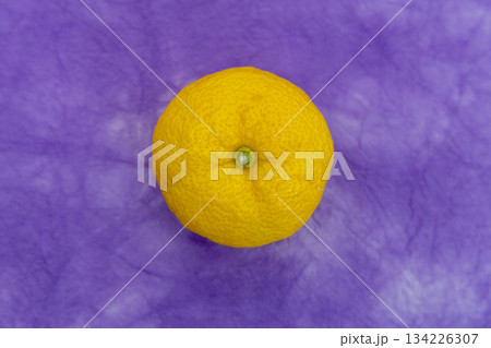 紫の和紙背景に置かれた柚子一つ 冬至や和風素材のイメージ 134226307