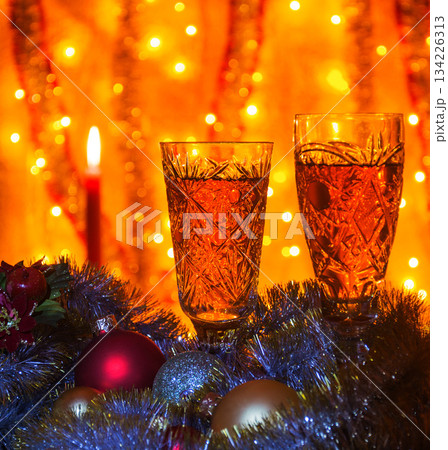 Wine glasses with champagne and a burning candle on a blurred background Wine glasses with champagne and a burning candle on a blurred background 134226313