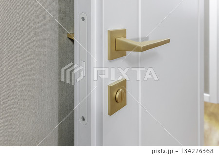 Golden Door Handle and Lock on White Interior Door in Modern Apartment Golden Door Handle and Lock on White Interior Door in Modern Apartment 134226368