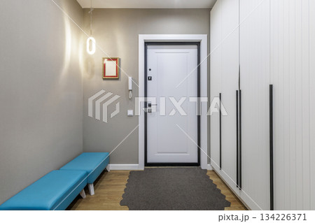 Bright Hallway with White Entrance Door and Blue Bench in Modern Apartment 134226371