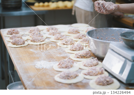 Cook puts the filling in the meat pies 134226494