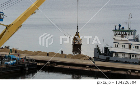 River cargo crane - process of loading sand from the barge to the ship 134226504