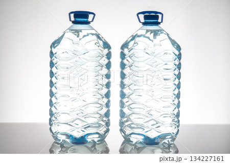 Two large plastic water bottles with blue caps  134227161