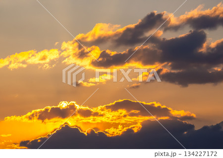 Ethereal sky filled with heavy clouds and golden light rays breaking through at sunset 134227172