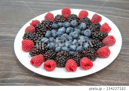 raspberries, blueberries and blackberries on a white plate. Vitamin and Diet Food raspberries, blueberries and blackberries on a white plate. Vitamin and Diet Food 134227182