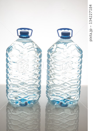 Two large plastic water bottles with blue caps and textured design Two large plastic water bottles with blue caps and textured design 134227184