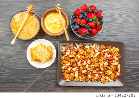A wooden table displays a healthy spread: a bowl of honey with a dipper A wooden table displays a healthy spread: a bowl of honey with a dipper 134227205